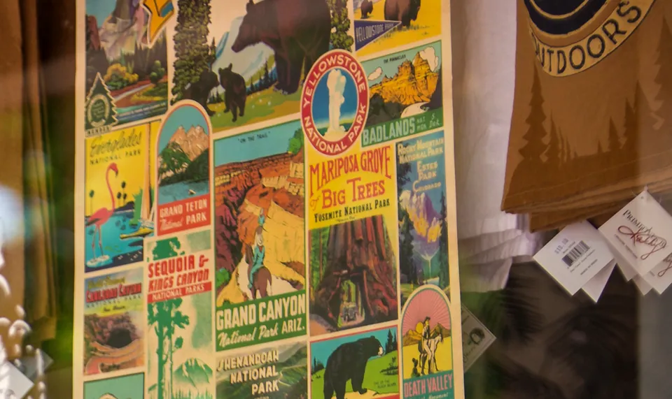 Shop window lettered 'High Cotton ...Celebrating Southern Style' with a national parks poster and cotton bolls on display inside.