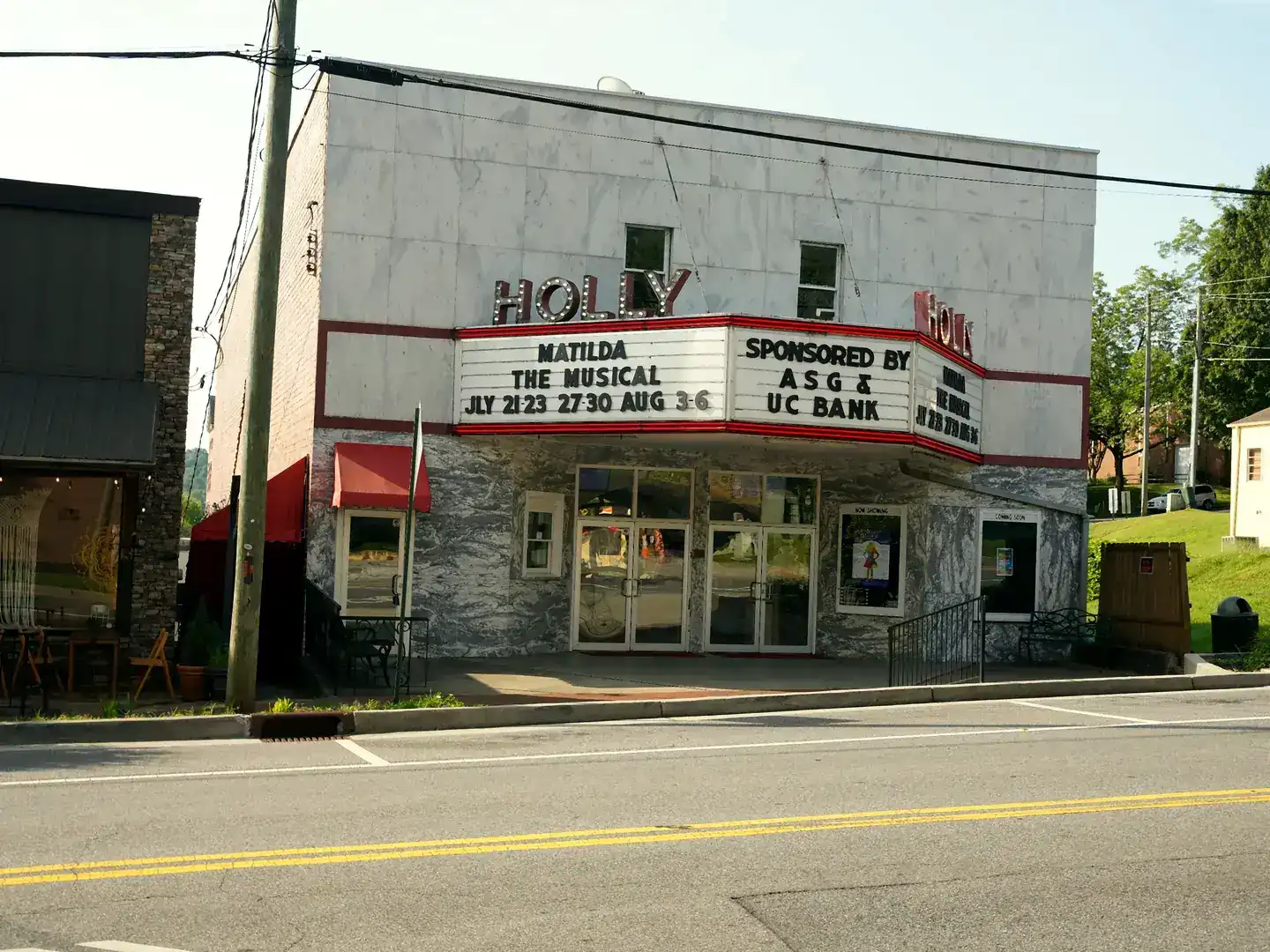 White marble facade of the Holly Theater in Dahlonega with red HOLLY lettering and a marquee advertising Matilda The Musical.