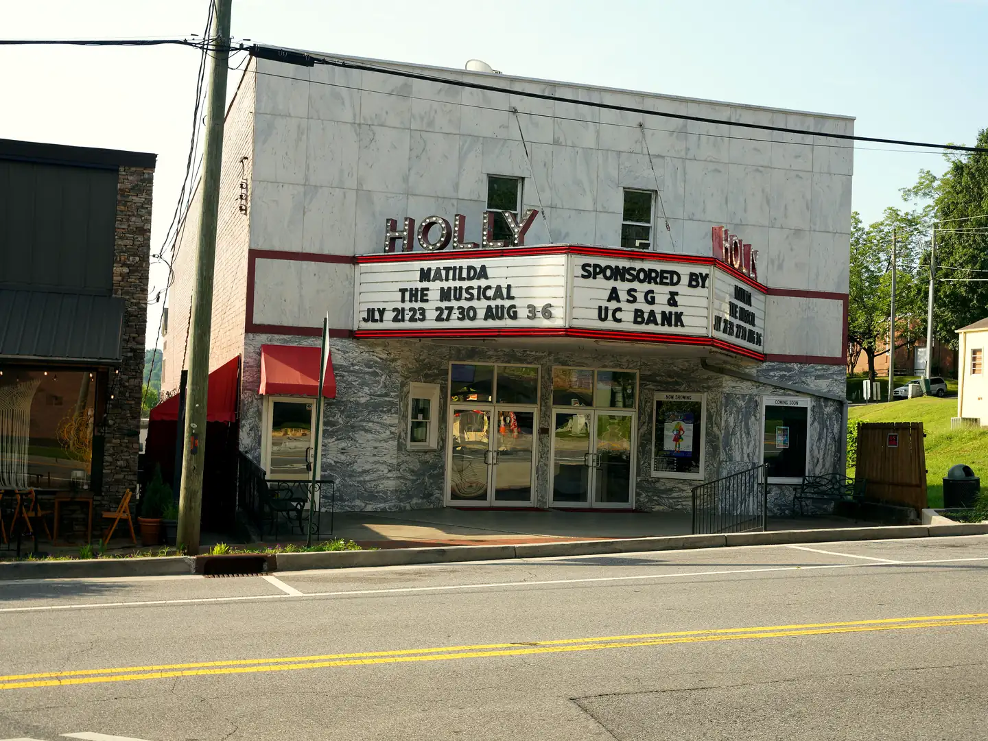 White marble facade of the Holly Theater in Dahlonega with red HOLLY lettering and a marquee advertising Matilda The Musical.
