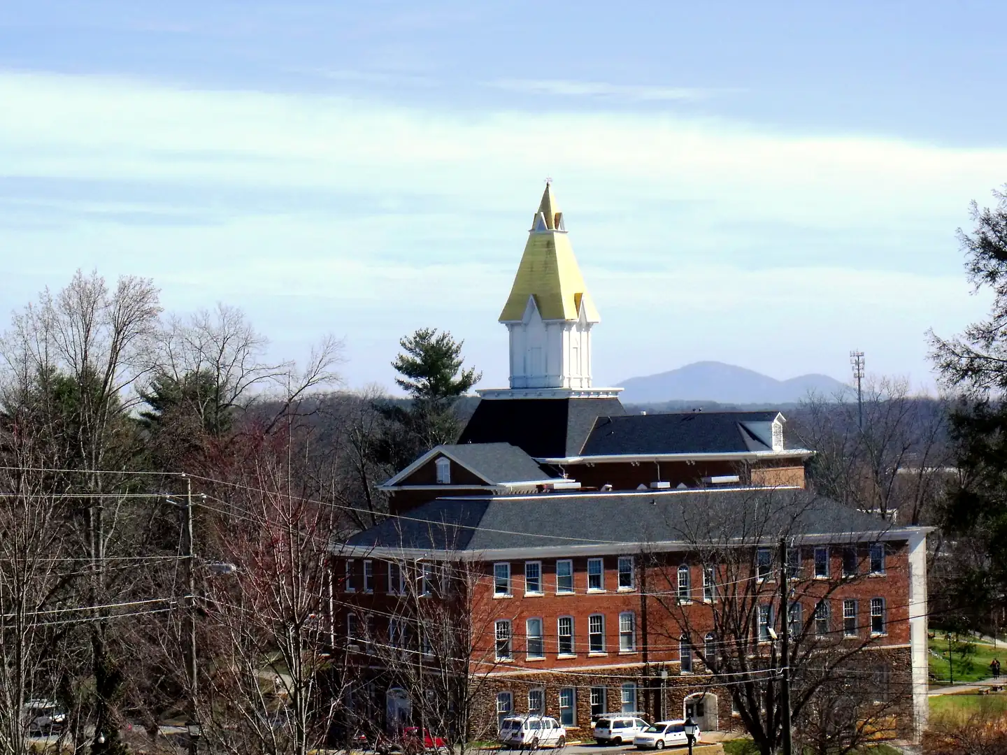 Gold-topped white steeple of Price Memorial Hall at the University of North Georgia, with a blue mountain on the horizon behind it.